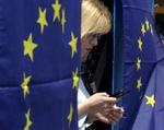 Kvinde står mellem to EU-flag i Cyperns hovedstad Nicosia. Det bliver kun den græske del af Cypern, der i dag optages, mens den nordlige, tyrkiske del indtil videre må vente. - Foto: AP 