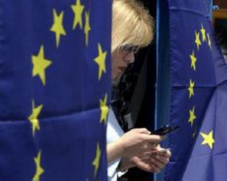 Kvinde står mellem to EU-flag i Cyperns hovedstad Nicosia. Det bliver kun den græske del af Cypern, der i dag optages, mens den nordlige, tyrkiske del indtil videre må vente. - Foto: AP 