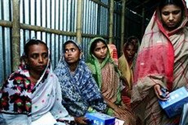 Ved et møde med Grameen Bank har Nurelli Begum (til venstre) netop modtaget en splinterny Nokia 3315. Hun er nu en af 50.000 kvinder i Bangladesh, der fungerer som sin landsbys telefondame.   Foto: Michael Lund 