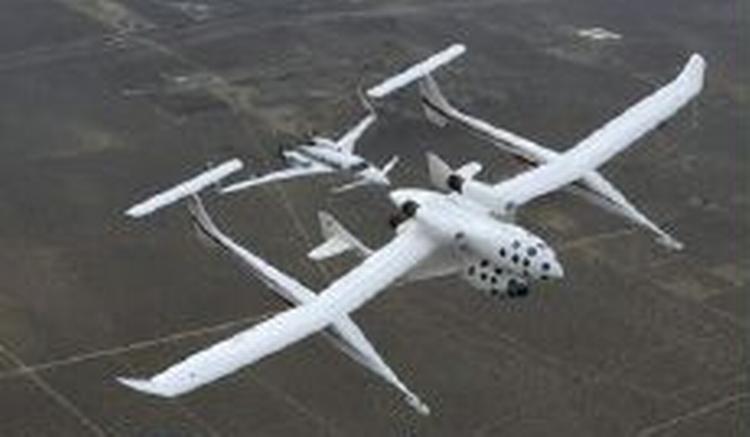 SpaceShipOne ligger som et lille fartøj under det specialbyggede fly White Knight, der bringer SpaceShipOne til kanten af rummet. Bag White Knight ligger et følgefly. - Foto: AP 