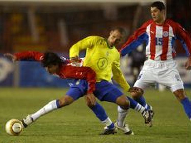 Den brasilianske målscorer Luis Fabiano (gul) i kamp med Paraguays Benitez. - Foto: AP 