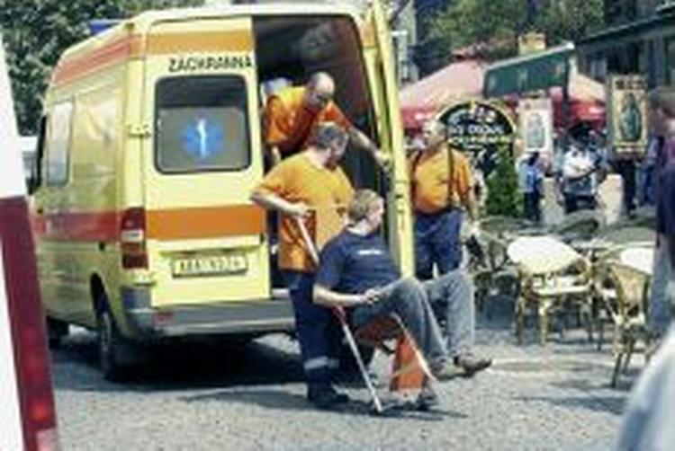 I første omgang forlød det, at angrebet var udløst af en håndgranat, men der var tale om en bombe gemt under en bil. Her hjælpes en af de sårede ind i en ambulance. - Foto: AP 