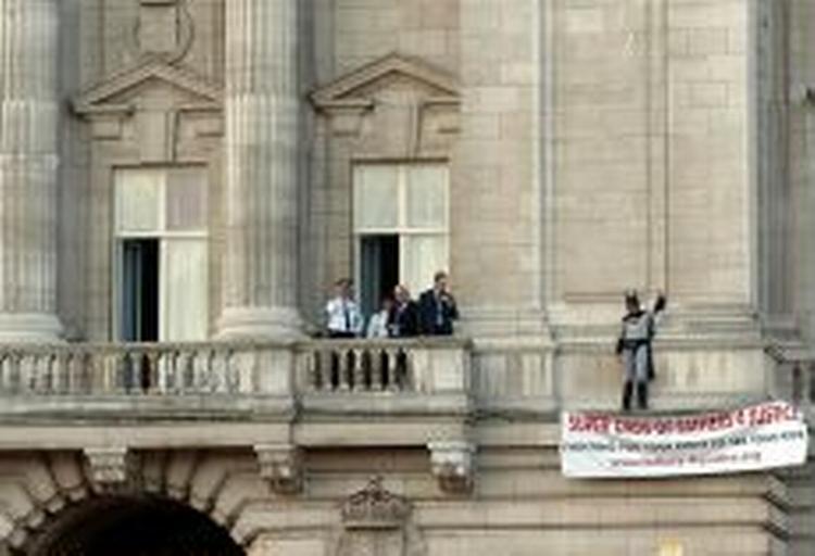 Fra en af balkonerne har den falske Batman spredt et banner ud, hvor der står 'Super dads of Fathers 4 Justice', mens han råber slagord. - Foto: AP 