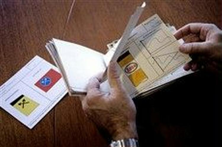 Lovligt nyts udsendte benytter sig af sin demokratiske ret til at gennemgå arkivet over rederiers mærker. På bordet ligger arkivkortet med Grønlands hjemmestyres skorstensmærke og rederiflag, i stakken ses Essos skorsten. 