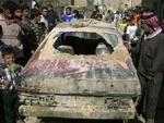 Irakere samles om en smadret bil efter nattens bombardementer i Sadr City. - Foto: AP 