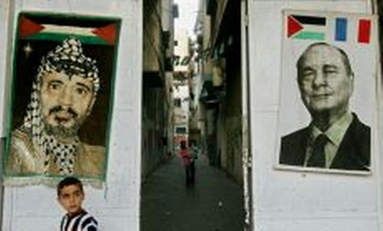 En tæppe i Gaza By med en indvævet fremstilling af Arafat ved siden af en plakat med et fotografi af den franske præsident Chirac. Mange palæstinensere er taknemmelige over den franske hjælp til Arafat. - Foto: AP 