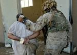 En uidentificeret soldat fører en formodet irakiske oprørere væk fra togstationen i Fallujah. - Foto: AP 