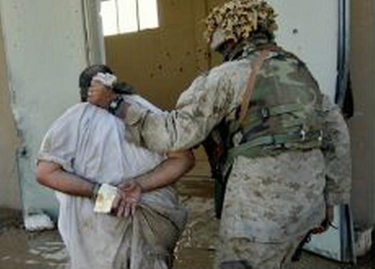 En uidentificeret soldat fører en formodet irakiske oprørere væk fra togstationen i Fallujah. - Foto: AP 