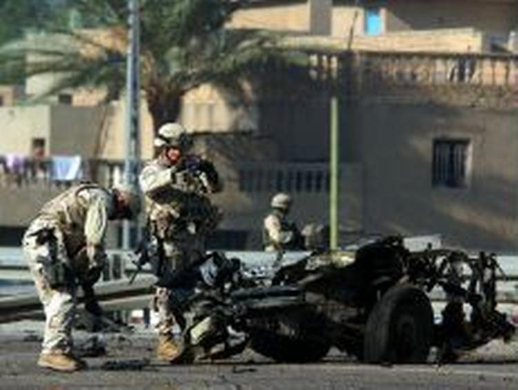 Amerikanske soldater i det vestlige Bagdad tager billeder af en bil, der tidligere i dag eksploderede nær en amerikansk kortege og sårede fem amerikanere. - Foto: AP 