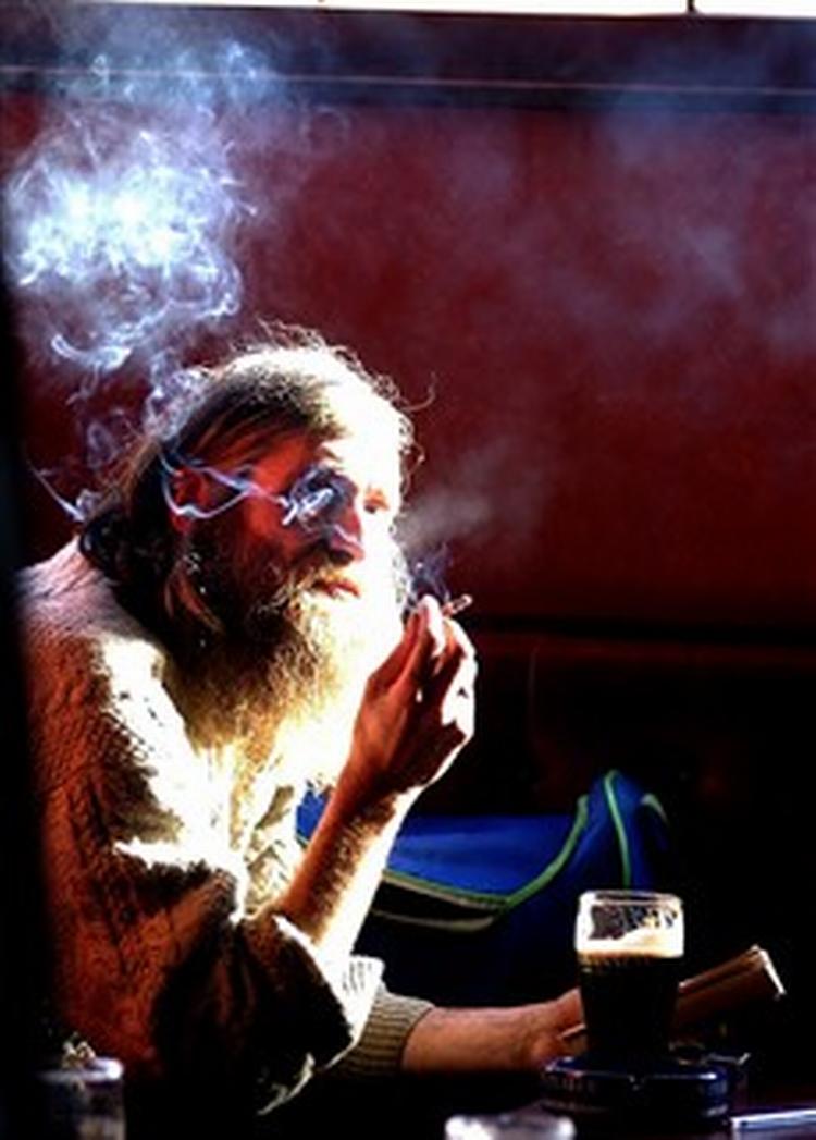 En mand napper en smøg og en øl på en pub i Irland i februar i år. En måneden senere var halvdelen af aktiviteterne forbudt. - Foto: AP 