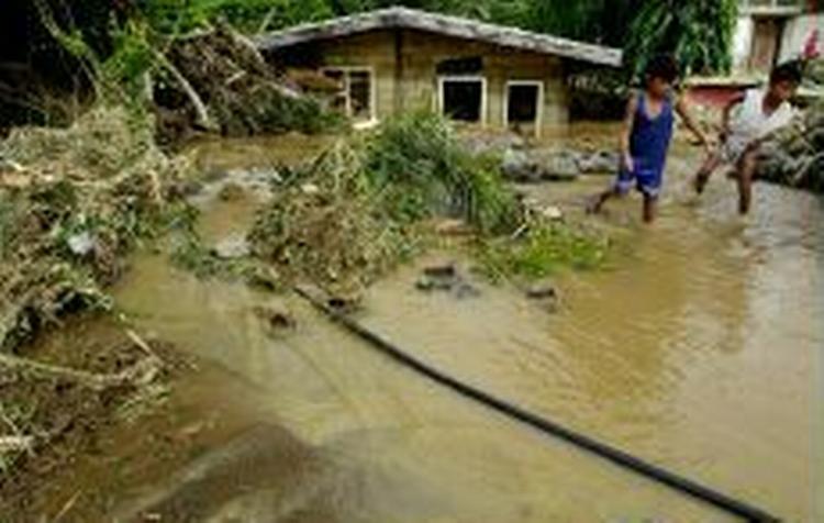 To børn passerer et oversvømmet hus i byen Dingalan, 70 kilometer øst for Manila. - Foto: AP 