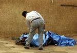 En undersøger ét af ofrene efter en eksplosion uden for den 'Grønne Zone' i Bagdad. - Foto: AP 
