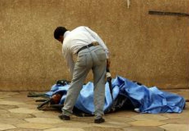En undersøger ét af ofrene efter en eksplosion uden for den 'Grønne Zone' i Bagdad. - Foto: AP 