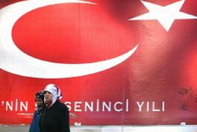 To tyrkiske kvinder passerer en plakat med det tyrkiske flag i Istandbul. - Foto: AP 