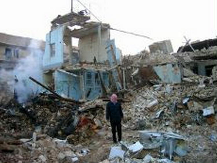 En mand står midt i de rygende ruiner i Najaf. - Foto: AP 