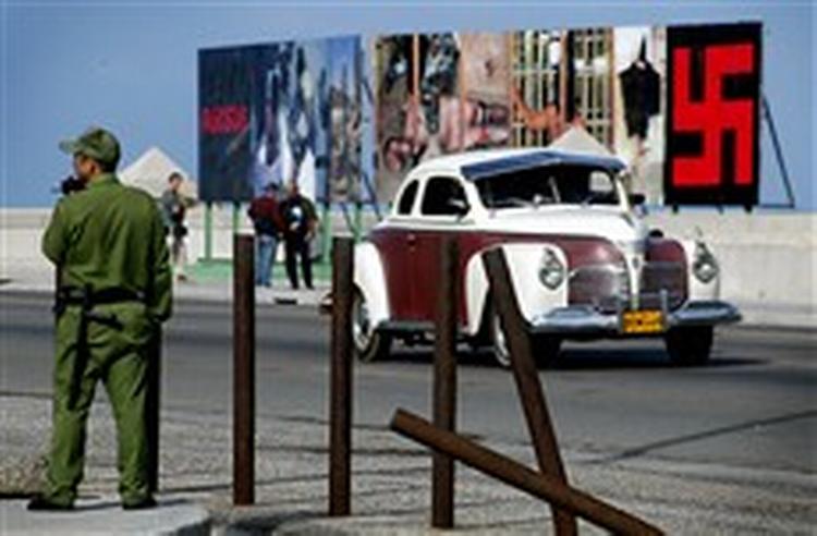 Et hagekors og plakater med torturofre fra Abu Ghraib-fængslet i Irak er cubanernes svar på en amerikansk juleudsmykning, der henleder opmærksomheden på 75 fængslede systemkritikere.   Foto: Cristobal Herrera, AP 