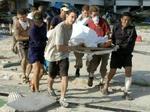 En såret turist bæres væk af venner og redningsfolk på Phi Phi-øen i Thailand. - Foto: AP 