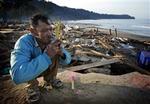 Kusol Wetchakul beder for sin søsters sjæl i daggryet ved stranden nær Khao Lak i Thailand. Hun blev trukket ud med vandet.   Foto: David Longstreath/AP 