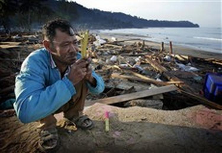 Kusol Wetchakul beder for sin søsters sjæl i daggryet ved stranden nær Khao Lak i Thailand. Hun blev trukket ud med vandet.   Foto: David Longstreath/AP 