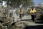 Indonesere på motorcykler kører gennem brokker og ruiner i den hårdt ramte by Aceh. - Foto: AP 
