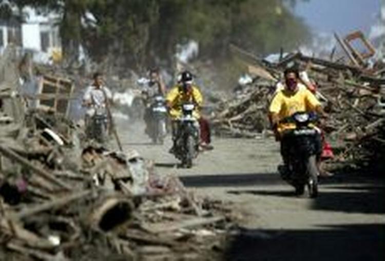 Indonesere på motorcykler kører gennem brokker og ruiner i den hårdt ramte by Aceh. - Foto: AP 
