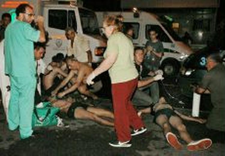 Kvæstede bringes uden for den brændende bygning, hvor redningsfolk venter. - Foto: AP 