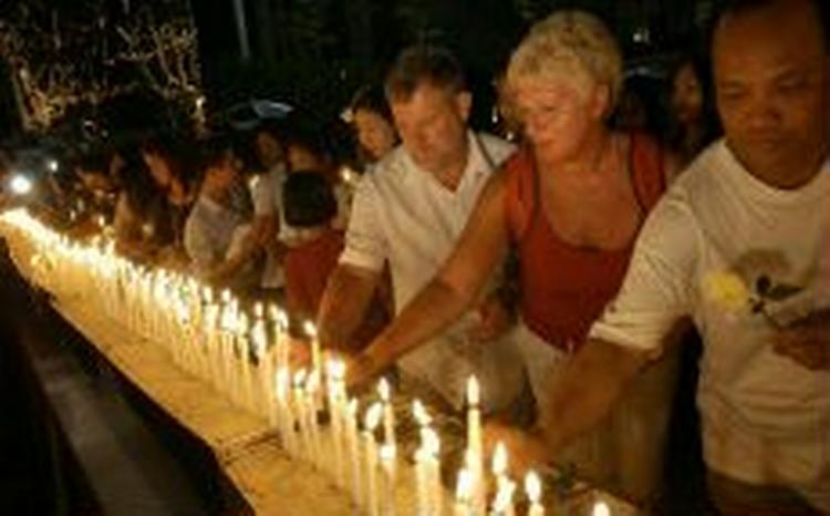I Thailand er al udendørs fejring af nytårsaften droppet til fordel for mindeceremonier for de omkomne. Her tænder thailændere og udlændinge stearinlys for de døde i Phuket. - Foto: AP 