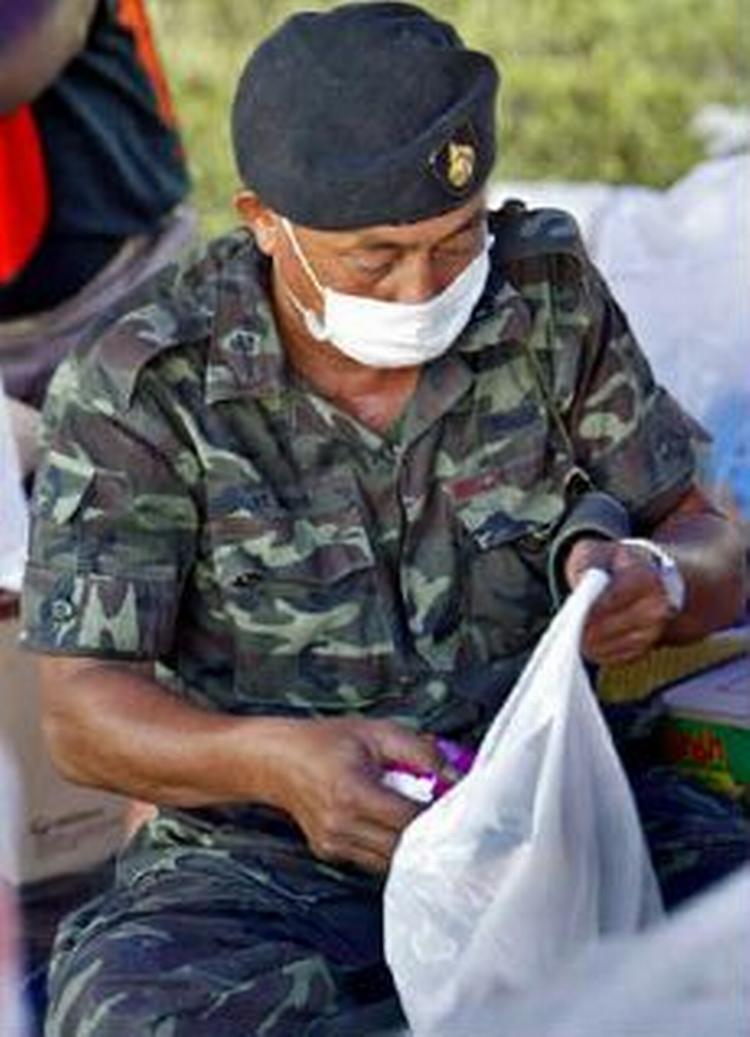 En thailandsk soldat pakker nødhjælp i en pose til overlevende. - Foto: AP 