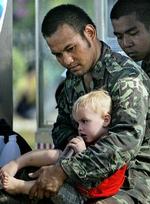 En thailandsk soldat sidder med en udenlandsk dreng på skødet i et nødcenter i byen Patong. - Foto: AP 