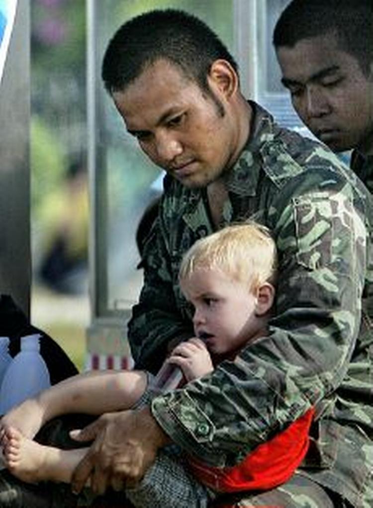 En thailandsk soldat sidder med en udenlandsk dreng på skødet i et nødcenter i byen Patong. - Foto: AP 