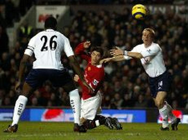 Manchester Uniteds hurtige portugiser Christiano Ronaldo på knæ mellem to Tottenham-forsvarere. - Foto: AP 