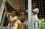 Flodbølgeofre kigger ud gennem hegnet rundt om en midlertidig nødlejr på en skole i byen Oddamavadi i Sri Lanka. - Foto: AP 