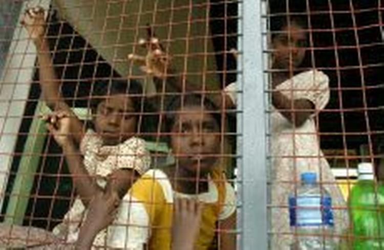 Flodbølgeofre kigger ud gennem hegnet rundt om en midlertidig nødlejr på en skole i byen Oddamavadi i Sri Lanka. - Foto: AP 
