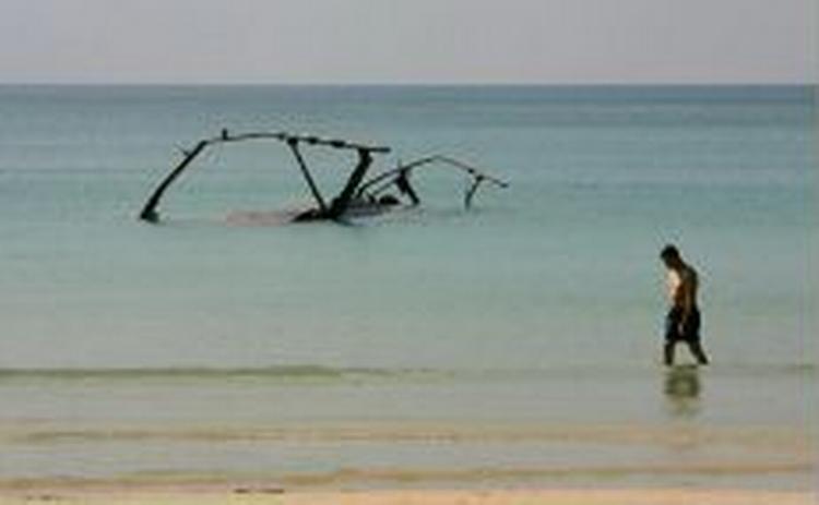 En britisk turist spadserer langs strande i ét af ramte områder i Thailand. - Foto: AP 
