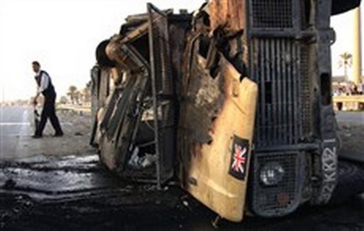 Irakisk politimand opsamler våben fra en udbrændt britisk kampvogn efter et trafikuheld i Bagdad.   Foto: Mohammed Khalil/AP 