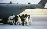 Elitesoldater eskorterer fanger ud af et amerikansk fly i Kandahars lufthavn i januar 2002, som anbringes i en fangelejr ved lufthavnen.   Foto: Dario Lopez-Mills/AP 