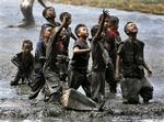 Flygtningebørn forsøger at fange noget af den nødhjælp, der kastes ned fra helikopter i udkanten af Banda Aceh i Indonesien.   Foto: Eugene Hoshiko, AP 