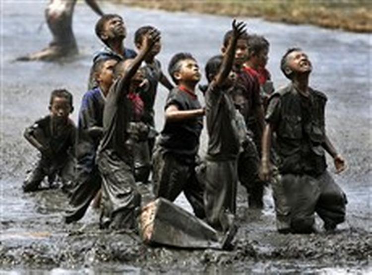 Flygtningebørn forsøger at fange noget af den nødhjælp, der kastes ned fra helikopter i udkanten af Banda Aceh i Indonesien.   Foto: Eugene Hoshiko, AP 