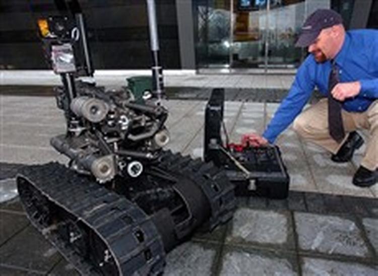 En design-ingeniør i våbenfabrikken Foster-Miller demonstrerer firmaets nye robot, der skal sættes ind i Irak. Den kan angiveligt ramme plet hver gang.   Foto: Mike Derer, AP 