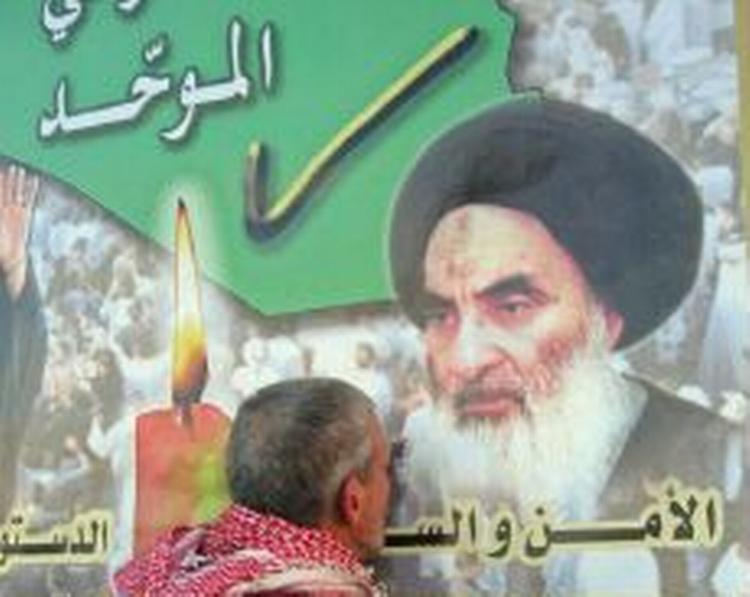 En mand kysser en valgplkat af al-Sistani, hvis alliance nu ligger til valgsejr. - Foto: AP 