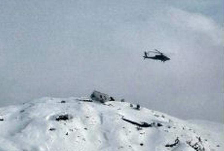 Halefinnen fra det nedstyrtede Boeing 727 fly stikker op af sneen, mens en redningshelikopter cirkulerer over vragresterne. - Foto: AP 