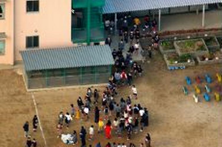Elever bliver gelejdet ud i skolegården efter knivoverfaldet på skolen i byen Neyagawa nær Osaka. - Foto: AP 