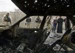 Amerikanske soldater og civile irakere betragter et bilvrag efter en af eksplosionerne i Bagdad. - Foto: AP 