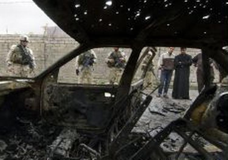 Amerikanske soldater og civile irakere betragter et bilvrag efter en af eksplosionerne i Bagdad. - Foto: AP 