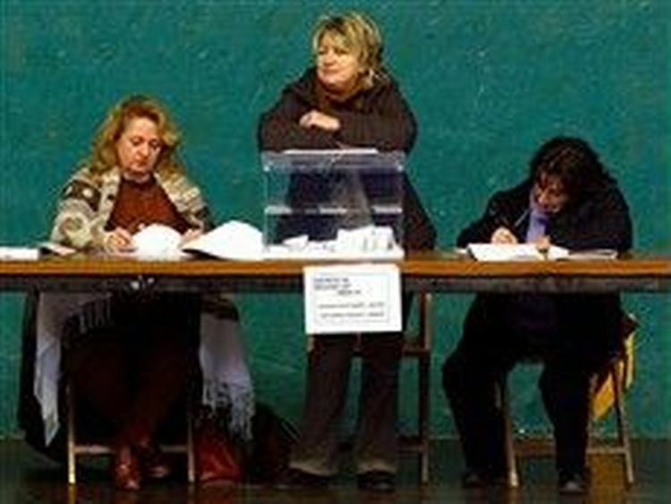 Valgtilforordnede vogter over stemmeboksene i et af de halvtomme valglokaler i Spanien. - Foto: AP 