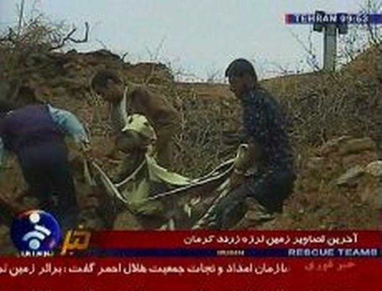 Unge mænd redder familiemedlem ud af murbrokkerne. - Foto fra iransk tv: AP 