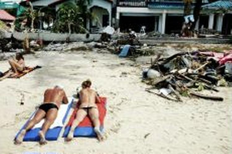 Martin Lehmanns vinderbillede af et dansk par, der soler sig på stranden i Puhket, Thailand, mens oprydningsarbejdet efter flodbølgen foregår omkring dem. - Foto: Martin Lehmann 
