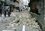 Fodgængere betragter en væltet mur i byen Fukuoka. - Foto: AP 