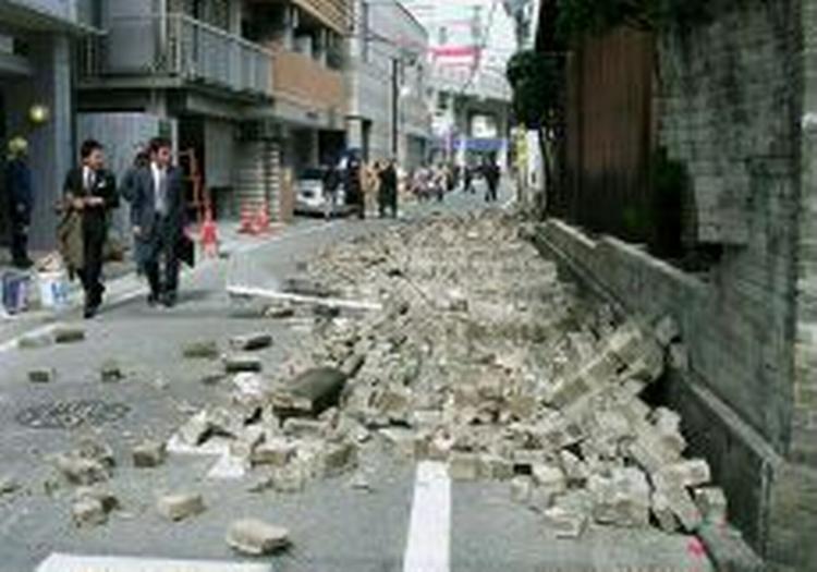 Fodgængere betragter en væltet mur i byen Fukuoka. - Foto: AP 