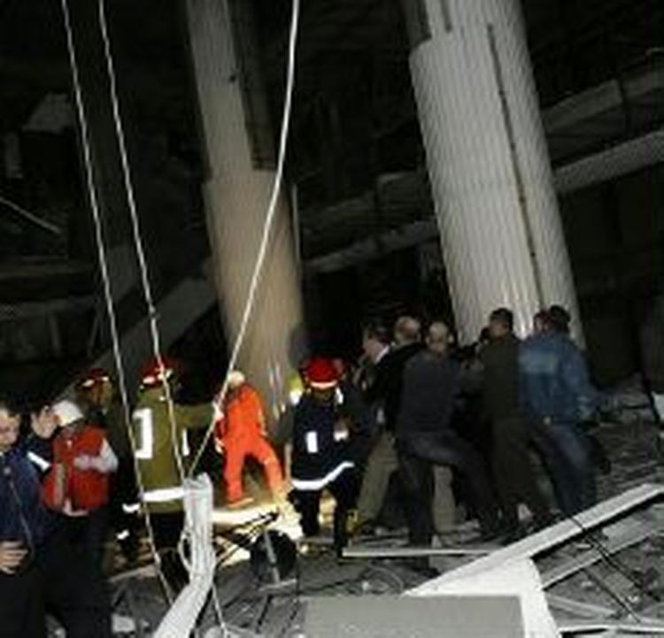 Redningsfolk måtte flygte, da en del af taget i indkøbscentret styrtede sammen. - Foto: AP 